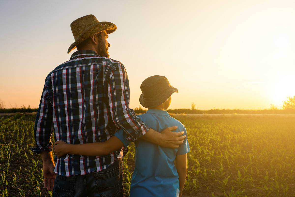 Father and Son Standing in Field at Sunset
